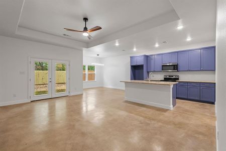 Kitchen featuring sink, an island with sink, stainless steel appliances, and a tray ceiling