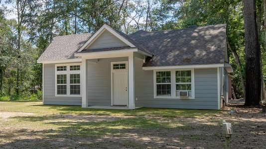 The home has a welcoming front entrance and multiple windows for natural light. A serene natural setting with mature trees.