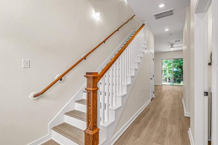 First floor entry with powder room to the right, stained wood accented stairway and living spaces beyond.