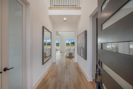 Corridor with a towering ceiling and light hardwood / wood-style floors