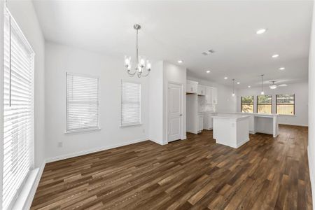 Unfurnished living room with ceiling fan with notable chandelier and dark hardwood / wood-style flooring