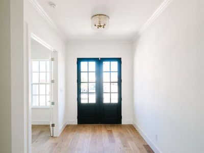 Foyer featuring french doors, crown molding, light hardwood / wood-style floors, and a chandelier