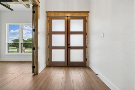 Foyer entrance featuring light hardwood / wood-style floors and french doors