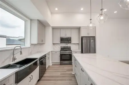 Sleek lines with quartz counters and backsplash.