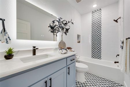 Full bathroom with vanity, toilet, tiled shower / bath combo, and tile patterned floors