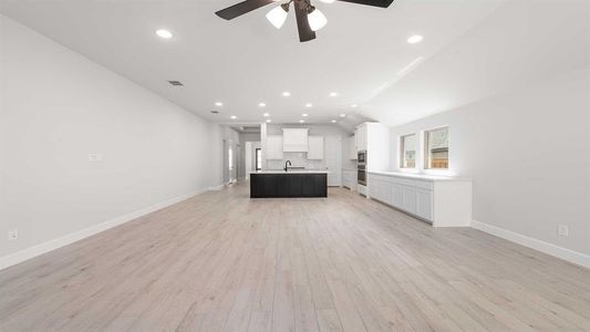 Unfurnished living room with lofted ceiling, light hardwood / wood-style floors, sink, and ceiling fan