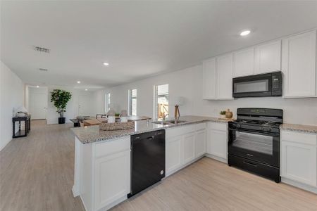 Kitchen featuring black appliances, kitchen peninsula, light wood-type flooring, and white cabinetry