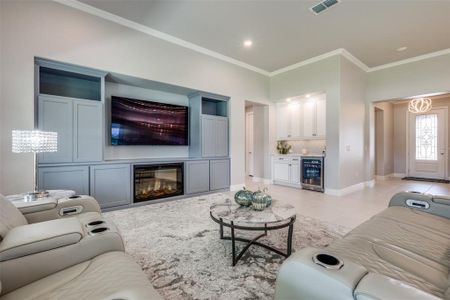 Living room with crown molding, wine cooler, and light tile patterned flooring