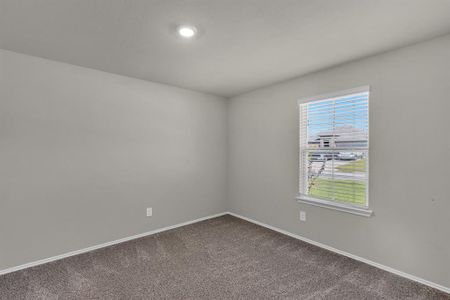 Guest bedroom number 1 is located to the right of the entryway, featuring soft carpet flooring, a large window for natural light, and a spacious layout perfect for guests or a home office.