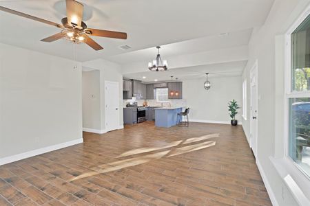 Unfurnished living room with dark wood-type flooring and ceiling fan with notable chandelier