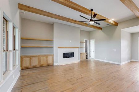 Unfurnished living room with light hardwood / wood-style floors, ceiling fan, and beamed ceiling