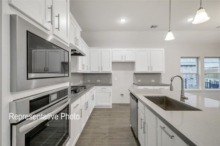 Kitchen featuring appliances with stainless steel finishes, tasteful backsplash, sink, decorative light fixtures, and hardwood / wood-style flooring