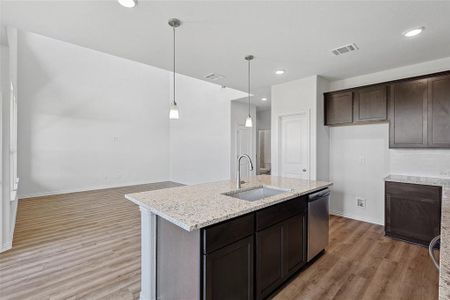 Kitchen with dishwasher, light hardwood / wood-style floors, decorative light fixtures, dark brown cabinetry, and sink