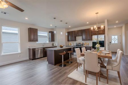 Dining area with light hardwood / wood-style flooring, sink, and ceiling fan with notable chandelier