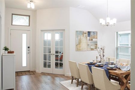 Dining space featuring french doors, light hardwood / wood-style flooring, lofted ceiling, and a notable chandelier