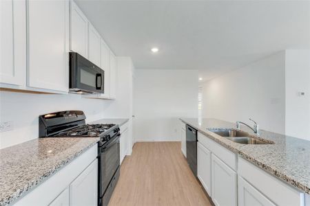 Kitchen featuring sink, black appliances, white cabinetry, and light wood-type flooring