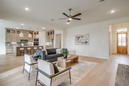 Living room featuring light hardwood / wood-style floors, crown molding, 10 ft ceilings, 8 ft doors, ceiling fan