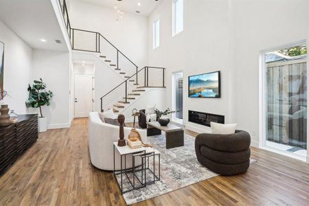 Living room with a healthy amount of sunlight, hardwood / wood-style flooring, and a high ceiling