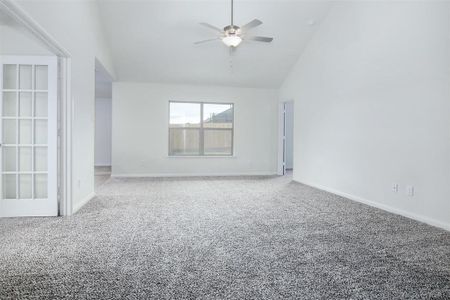 Carpeted spare room featuring ceiling fan and high vaulted ceiling