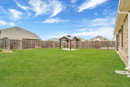 Spacious backyard with well-maintained lawn and wooden privacy fence, featuring a charming gazebo perfect for outdoor relaxation or entertaining.