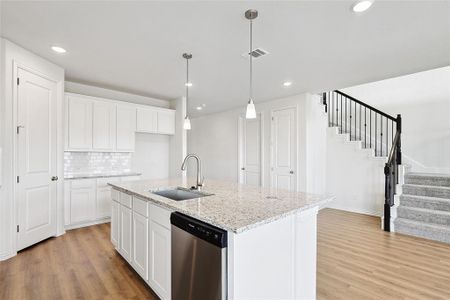 Kitchen with white cabinets, dishwasher, a center island with sink, and sink