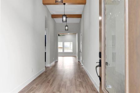 Light and bright foyer with natural wood toned beams and black iron pendant lighting