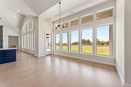 Unfurnished living room featuring light hardwood / wood-style flooring, high vaulted ceiling, and an inviting chandelier