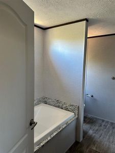 Bathroom featuring a tub, a textured ceiling, and wood-type flooring