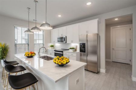 Kitchen featuring appliances with stainless steel finishes, white cabinets, sink, pendant lighting, and backsplash