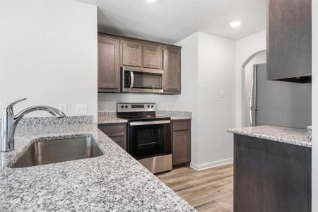 Kitchen featuring light hardwood / wood-style flooring, sink, light stone countertops, and appliances with stainless steel finishes