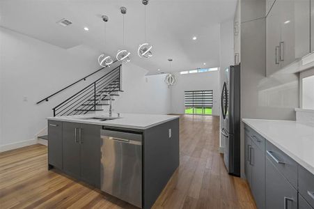 Kitchen with stainless steel appliances, pendant lighting, gray cabinets, and light wood-type flooring