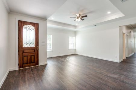 Entrance foyer featuring ceiling fan, a tray ceiling, ornamental molding, and dark hardwood / wood-style flooring