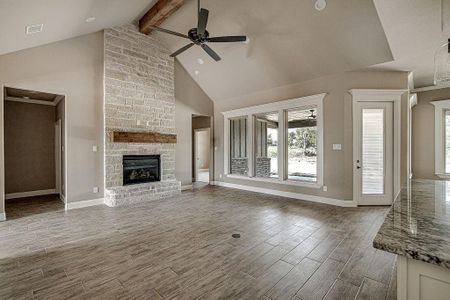 Unfurnished living room with high vaulted ceiling, brick wall, ceiling fan, and a large fireplace