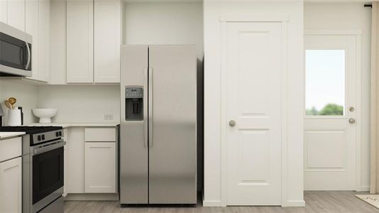 Kitchen with stainless steel appliances, white cabinets, and light hardwood / wood-style flooring