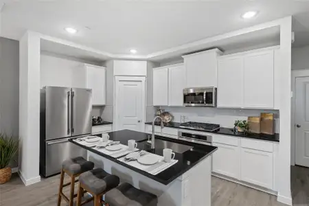 Kitchen with backsplash, stainless steel appliances, sink, a center island with sink, and light hardwood / wood-style floors