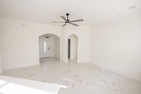 Empty room with ceiling fan and light tile floors