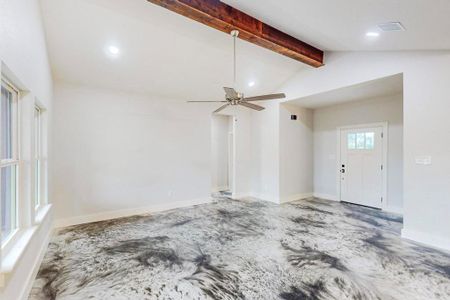 Unfurnished living room with vaulted ceiling with beams and ceiling fan