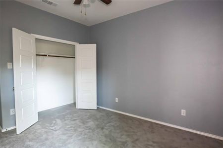 Unfurnished bedroom featuring a closet, dark colored carpet, and ceiling fan