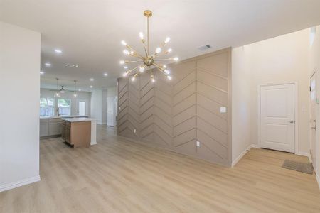 Unfurnished living room with light hardwood / wood-style floors and ceiling fan with notable chandelier