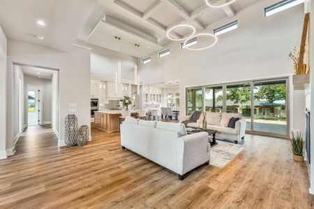 Living room with a towering ceiling, coffered ceiling, light wood-type flooring, and plenty of natural light