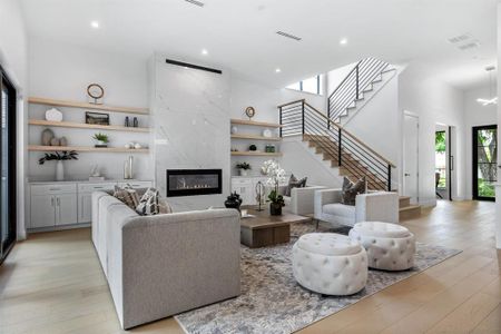 Living room with a high end fireplace, a towering ceiling, light hardwood / wood-style flooring, and a barn door