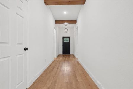 Corridor featuring beamed ceiling and light hardwood / wood-style floors