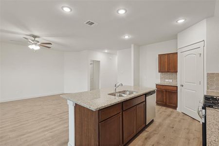 Kitchen featuring tasteful backsplash, an island with sink, stainless steel appliances, light hardwood / wood-style floors, and sink