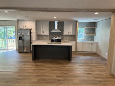 Kitchen with appliances with stainless steel finishes, wall chimney exhaust hood, dark wood-type flooring, and tasteful backsplash