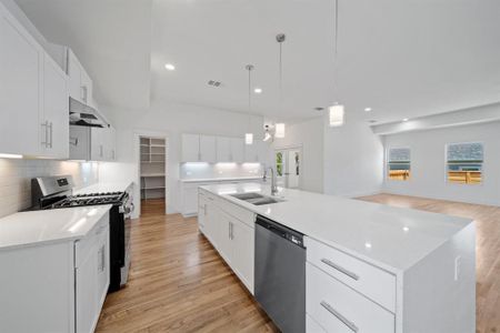 Kitchen with white cabinets, sink, light hardwood / wood-style floors, appliances with stainless steel finishes, and a kitchen island with sink