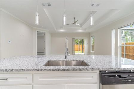 Kitchen featuring white REAL WOOD cabinets, sink, light stone countertops, dishwasher, and a double raised ceiling
