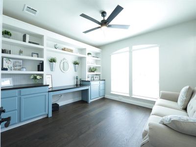 Office area with built in desk, ceiling fan, and dark wood-type flooring