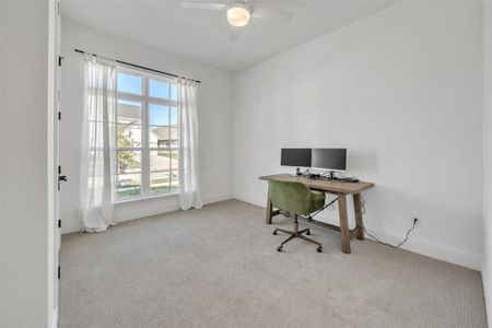 Front bedroom featuring light carpet, a wealth of natural light, and ceiling fan