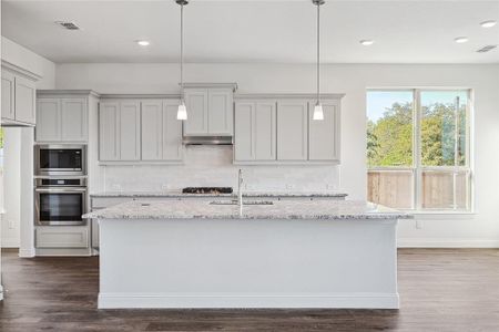 Kitchen featuring appliances with stainless steel finishes, light stone countertops, dark hardwood / wood-style flooring, and sink