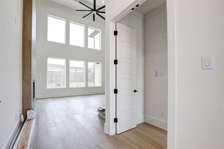 Hall with light hardwood / wood-style flooring and a towering ceiling